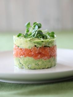 a white plate topped with a cucumber and salmon salad on top of lettuce