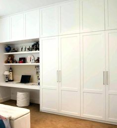 a bedroom with white cupboards and shelves in it