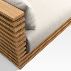 a stack of pillows sitting on top of a wooden bench next to a white pillow