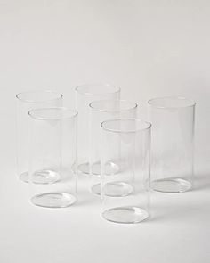 four clear glass vases sitting next to each other on a white surface with no one around them