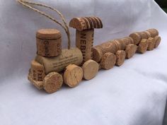 a train made out of wine corks sitting on top of a white cloth covered bench