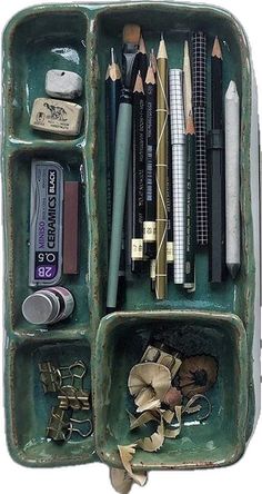 a green container filled with lots of different types of pens and pencils