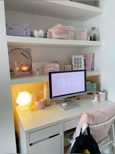 a desk with a computer on top of it next to a lamp and other items