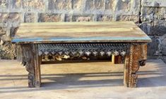 an old wooden table sitting in front of a stone wall