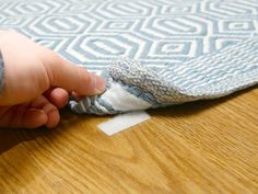 someone is removing the fabric off of a blue and white rug on a wooden floor