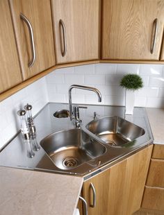 two stainless steel sinks in a kitchen with wooden cabinets