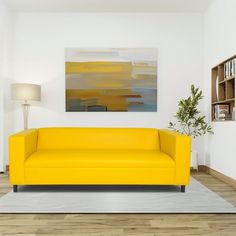 a living room with a yellow couch in the middle and a painting on the wall