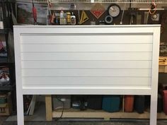 a white headboard sitting on top of a hard wood floor next to a shelf