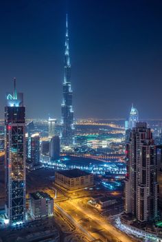 an aerial view of a city at night with lights and skyscrapers in the background