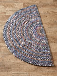 a blue and orange braided rug on a wooden floor with a wood flooring board