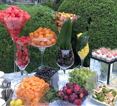 there are many different types of fruits on the table and desserts in glass vases