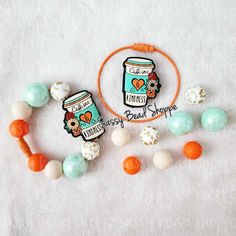 the beaded bracelet is next to an orange hoop and some beads on a white surface