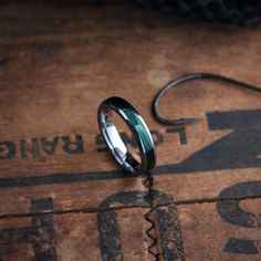 a black and green ring sitting on top of a wooden table next to a fishing hook