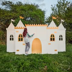 a woman standing in front of a fake castle made out of cardboard and painted white