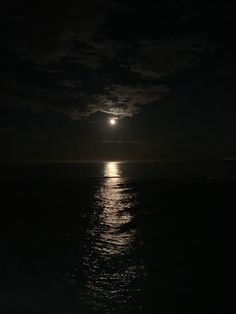 the moon is shining over the ocean at night