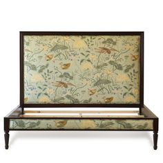 an upholstered bed frame with birds and flowers on the wall behind it, against a white background