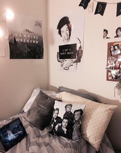 a bed with two pillows and pictures on the wall above it in a dorm room