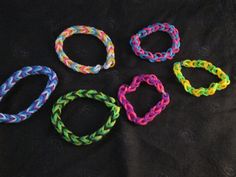 four different colored bracelets on a black surface with one knoted around the clasp