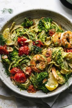 a bowl filled with pasta, shrimp and broccoli on top of a table