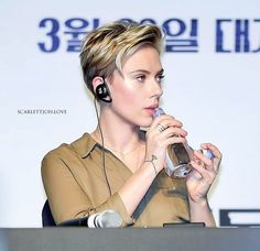 a woman with headphones on is holding a water bottle and listening to ear buds