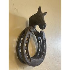 a cat head mounted on the side of a wall with two horseshoes attached to it