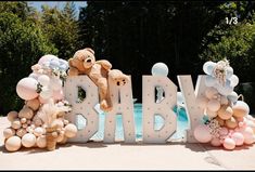 a teddy bear sitting on top of the letters for a baby shower