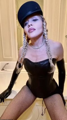 a woman in fishnet stockings and black hat sitting on a toilet with her legs crossed