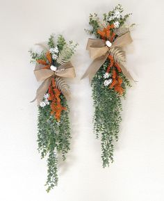 two wreaths with orange and white flowers hanging on the wall next to each other