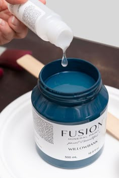 a person pouring blue paint onto a white plate