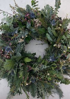 a wreath with greenery and berries hanging on the wall