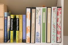 a book shelf filled with lots of books on top of white shelves next to wooden boxes