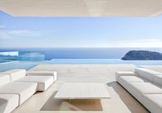 a white couch sitting next to a table on top of a floor near the ocean