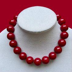 This unique necklace is made on strong stretch cord and is easily pulled on and off over the head. There is no clasp.  This stunning piece is meticulously handcrafted with CRANBERRY 20mm acrylic beads, strung on strong elastic for a comfortable fit. The knot is reinforced with jewelers glue, ensuring durability and longevity. With a variety of lengths to choose from, you can find the perfect fit for your style. Whether you're heading to a concert or a night out on the town, this necklace is the