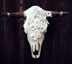 a white cow skull with flowers on it's head hanging from a wooden fence