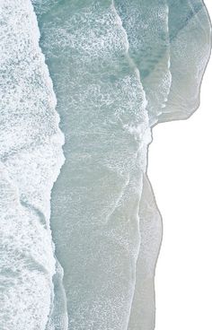 an aerial view of the ocean with waves coming in to shore and one person walking on the beach