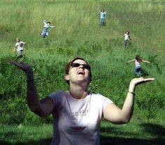 a woman in white shirt throwing a frisbee on field with people behind her