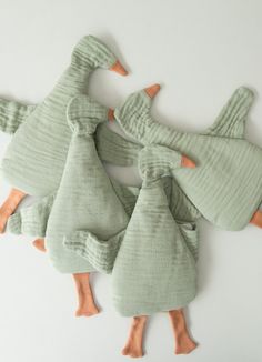 four green ducks with orange beaks are on the floor next to each other and one is wearing a sweater