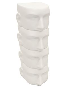 a white ceramic vase with multiple faces on it's sides and the top part of its head