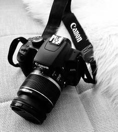 a camera sitting on top of a couch next to a white furnishing and a black strap