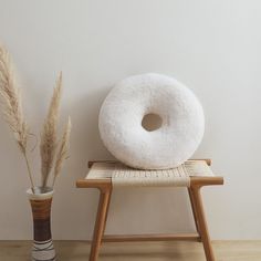 a white donut sitting on top of a wooden chair next to a vase