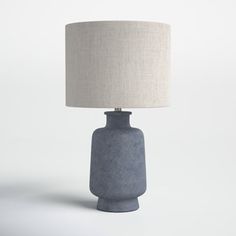 a gray table lamp with a white shade on it's base and a beige linen lampshade