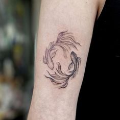 a woman's arm with a black and white koi fish tattoo on it