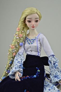 a doll sitting on top of a chair wearing a blue dress and long blonde hair