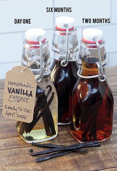 three bottles filled with vanilla syrup on top of a wooden table next to cinnamon sticks