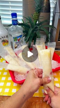 someone is holding up some food on a table with pineapples in the background