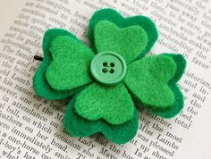 a green flower brooch sitting on top of an open book with a button in the center