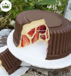 a chocolate cake with strawberries on top and one slice missing from it, sitting on a white plate