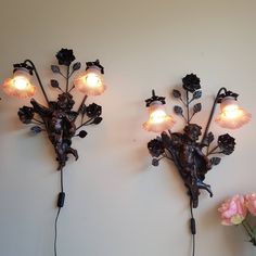 two wall sconces with flowers and lights attached to the wall next to each other