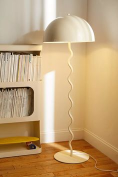 a lamp that is next to a book shelf with books on it in a room