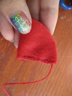 a person holding a piece of red material with white and green glitters on it